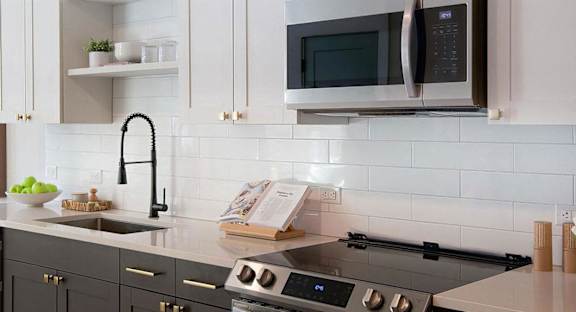 Sophisticated white countertops with subway tile backsplash and dark cabinets at Novel Cary