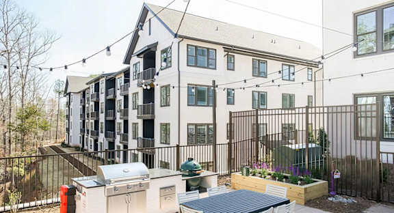 Spacious outdoor grilling station with two grills and herb planters at Novel Cary