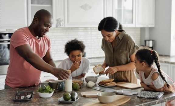 A family of four is preparing a meal together in the kitchen.
