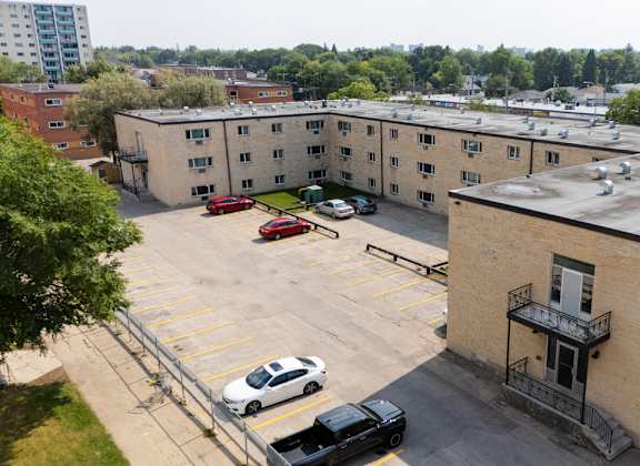 A parking lot with cars and a building with a balcony.