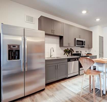 A modern kitchen with a refrigerator, microwave, oven, and sink.