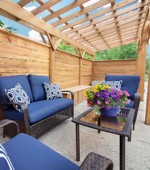 A wooden patio with a blue couch and a table with flowers.