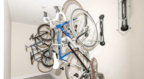A wall-mounted bike rack with several bicycles hanging on it.