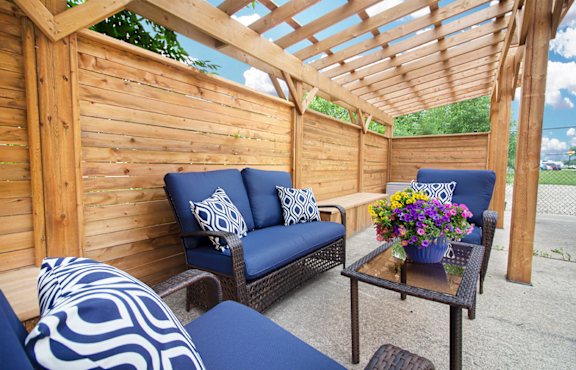 A wooden patio with a blue couch and a table with flowers.
