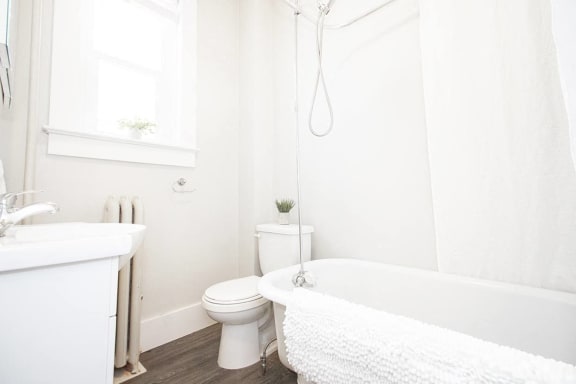 a white bathroom with a tub and a toilet and a sink