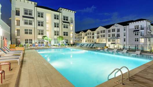 a swimming pool in front of an apartment building at night at The Eddy at Riverview, Smyrna, Georgia