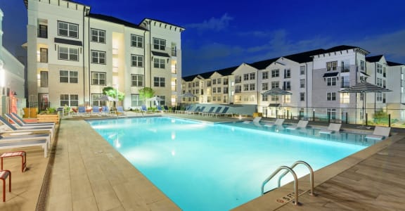 a swimming pool in front of an apartment building at night at The Eddy at Riverview, Smyrna, Georgia