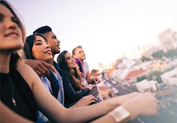 a group of people sitting on a balcony overlooking a city