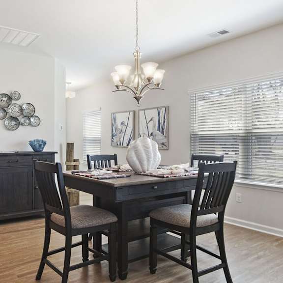 A dining room with a table set for two and a chandelier hanging from the ceiling at Stepping Stone at Bridgewater Apartments, South Carolina