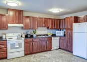 Thumbnail 38 of 42 - A kitchen with brown cabinets and white appliances.