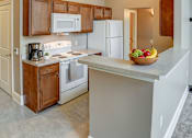 Thumbnail 26 of 28 - A kitchen with a white stove top oven and white microwave above it.