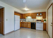 Thumbnail 30 of 31 - A kitchen with wooden cabinets and black appliances.