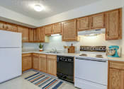 Thumbnail 27 of 28 - A kitchen with wooden cabinets and white appliances.