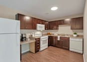 Thumbnail 44 of 45 - A kitchen with brown cabinets and white appliances.