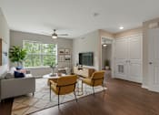 Thumbnail 43 of 45 - A living room with a grey couch, a yellow chair, a white cabinet, and a ceiling fan.