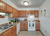 Thumbnail 26 of 29 - A kitchen with wooden cabinets and a white stove top oven.