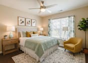Thumbnail 24 of 27 - A bedroom with a bed, a yellow chair, and a ceiling fan.