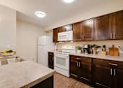 Thumbnail 25 of 27 - A kitchen with white appliances and brown cabinets.