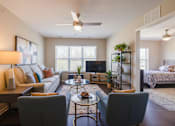 Thumbnail 23 of 27 - A living room with a grey couch, a coffee table, and a ceiling fan.