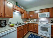 Thumbnail 40 of 43 - A kitchen with wooden cabinets and white appliances.