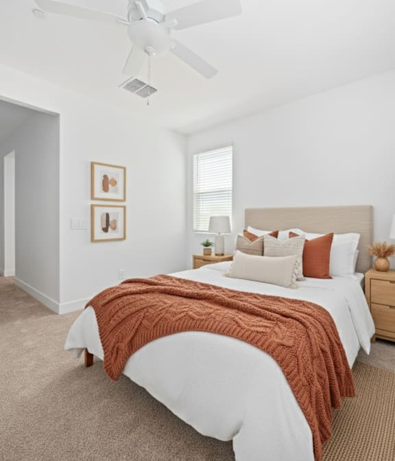 A bedroom with a bed, nightstand, and a plant.
