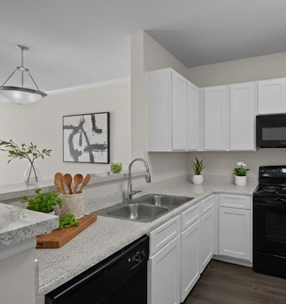A kitchen with black appliances and white cabinets.