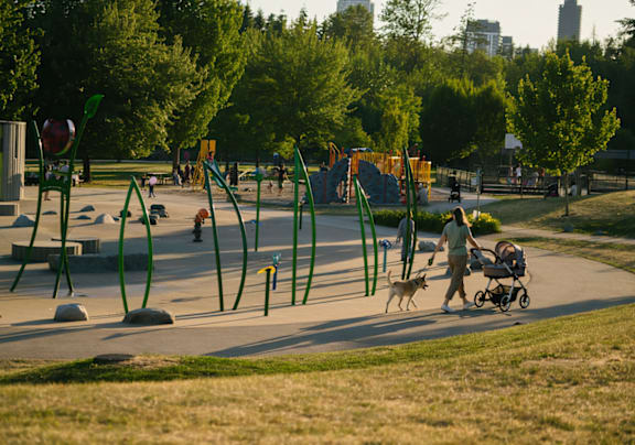 A park with a playground and people walking their dogs.