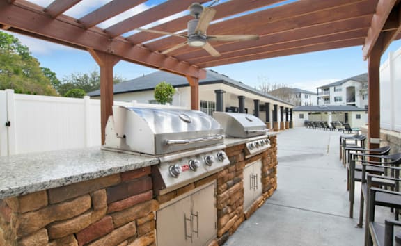 An outdoor kitchen with a grill and a fan.