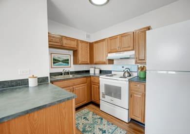 A kitchen with wooden cabinets and a white refrigerator at Fullerton Court Apartments, Chicago, IL