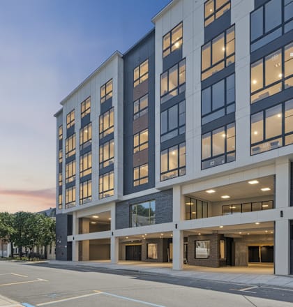 A modern building with a lot of windows and a parking lot in front.