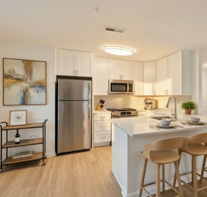 A modern kitchen with a white island and wooden bar stools.