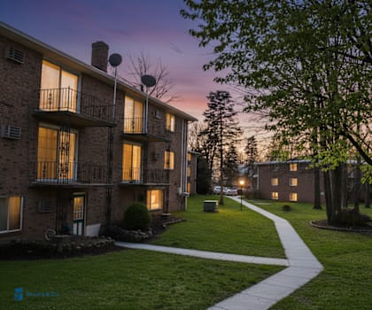 Apartment complex with a walkway and trees.