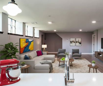 A red stand mixer is on a white counter in a modern living room.