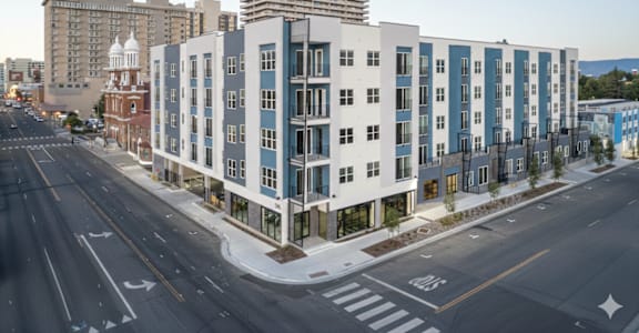 A street view of a city with apartment buildings and a crosswalk.