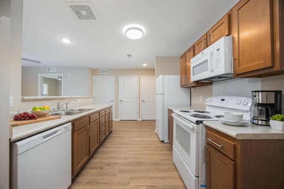 A kitchen with white appliances and wooden cabinets.