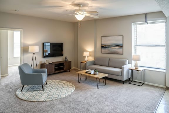 A living room with a grey chair, a grey sofa, a coffee table, and a painting on the wall.