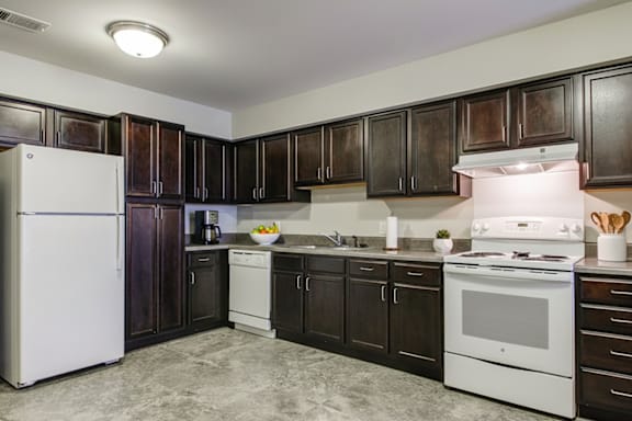A kitchen with white appliances and dark wood cabinets.
