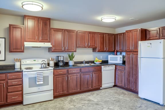A kitchen with brown cabinets and white appliances.