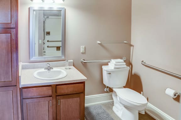 A white toilet is in a bathroom with a sink and mirror.