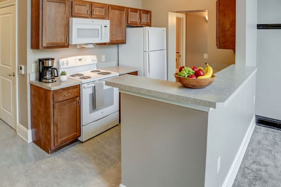 A kitchen with a white stove top oven and white microwave above it.
