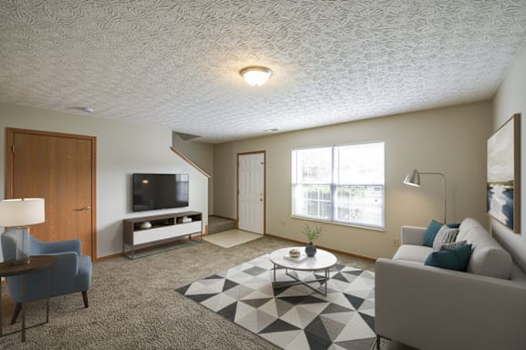 A living room with a grey couch, a coffee table, a television, and a lamp.