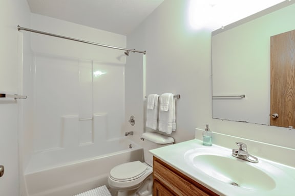 A white toilet sits next to a white bathtub in a bathroom.