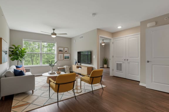 A living room with a grey couch, a yellow chair, a white cabinet, and a ceiling fan.