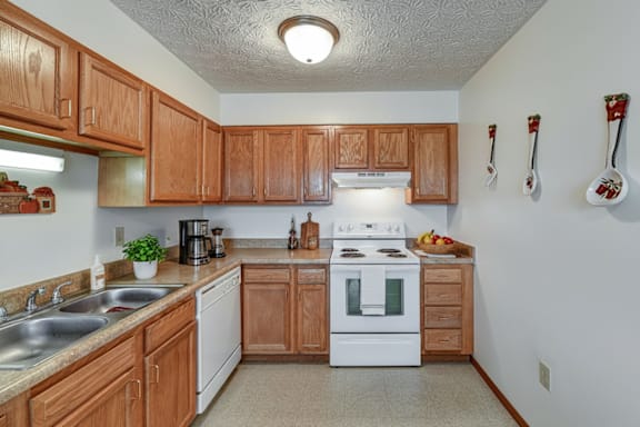 A kitchen with wooden cabinets and a white stove top oven.