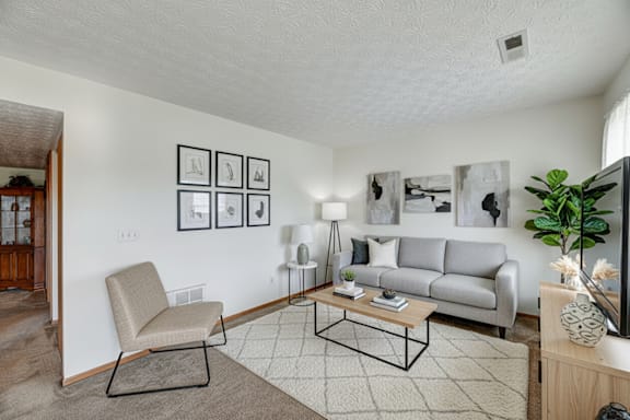A living room with a grey couch, a chair, a coffee table, and pictures on the wall.