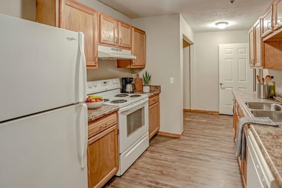 A kitchen with a white refrigerator, wooden cabinets, and a marble countertop.