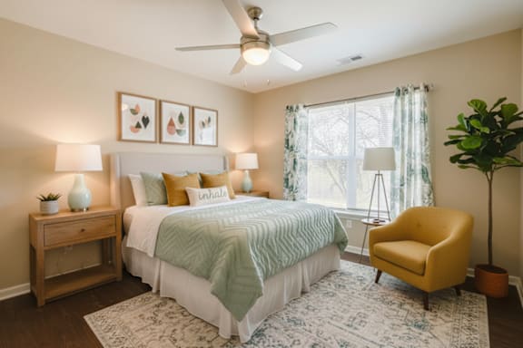 A bedroom with a bed, a yellow chair, and a ceiling fan.