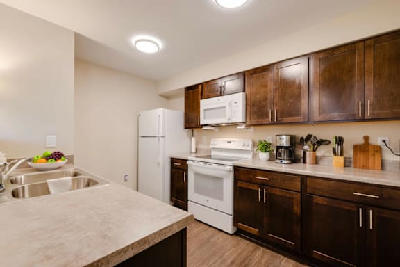 A kitchen with white appliances and brown cabinets.