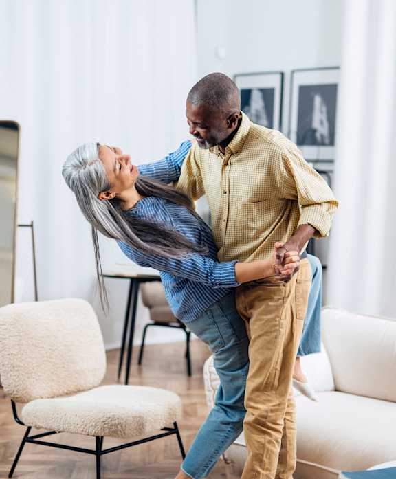 A man lifts a woman in a living room setting.