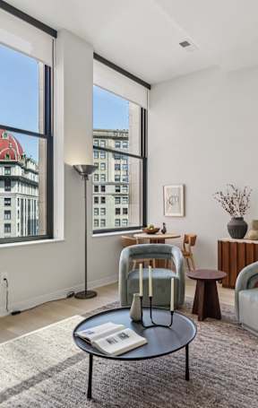 A living room with a black coffee table and a green chair. at LiveWell Apartments, Pittsburgh, PA, 15222